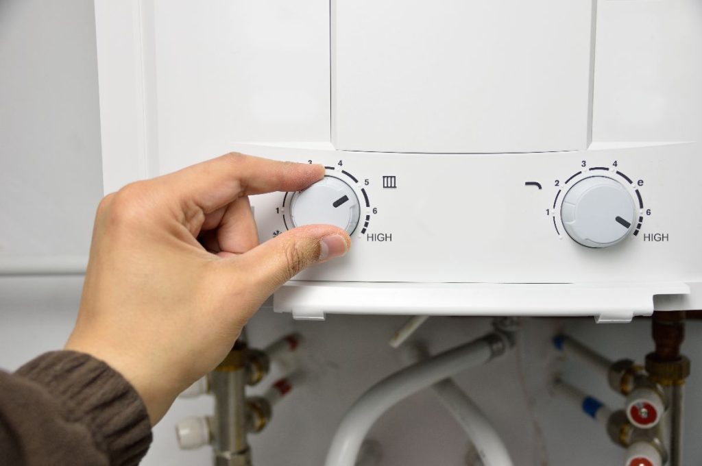 A heater with a person fixing a tankless water heater in Calgary, AB