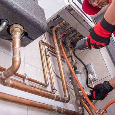 A plumber fixing a gas line for gas leak detection services in Calgary, AB