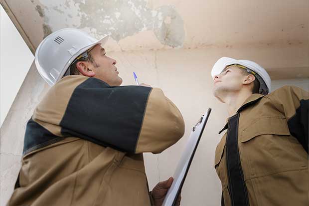 Staff analyzing ceiling that is leaking doing leak detection services in Calgary, AB