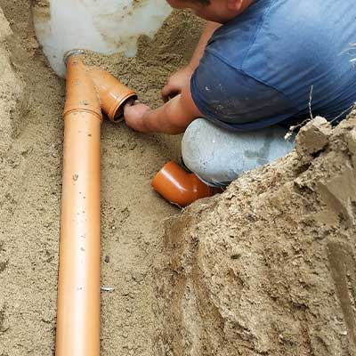 A person fixing a brown pipe doing sewer drain cleaning in Calgary, AB