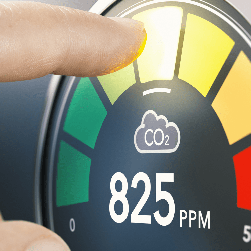 A finger pointing at a CO2 meter indicating a high level of 825 PPM.