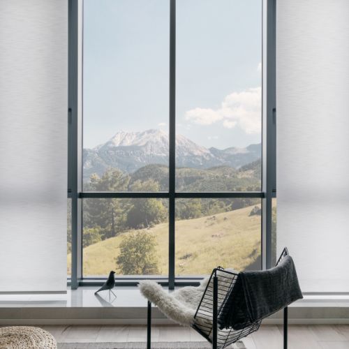 A black chair inside a room leaning towards a window overlooking a mountain and a forest in Calgary