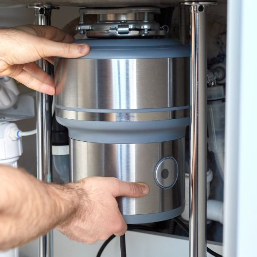 Plumber holding a garbage disposal device in a process of garbage disposal repairs in Calgary