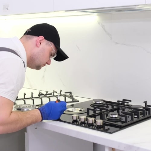 A person wearing gloves cleaning a stove top in Calgary.