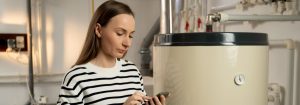 Person in striped shirt standing by a water heater holding a smartphone in Calgary.