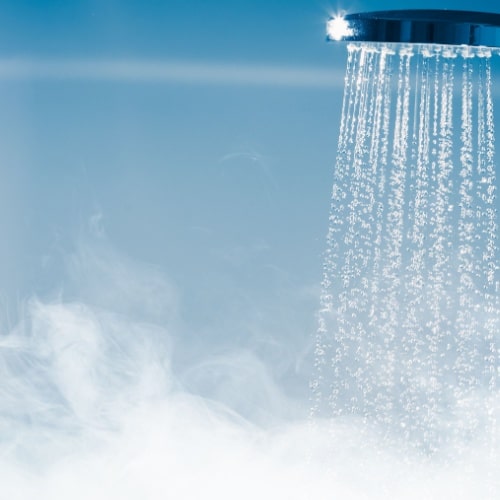 Shower head with water flowing and steam rising against a blue background in Calgary.